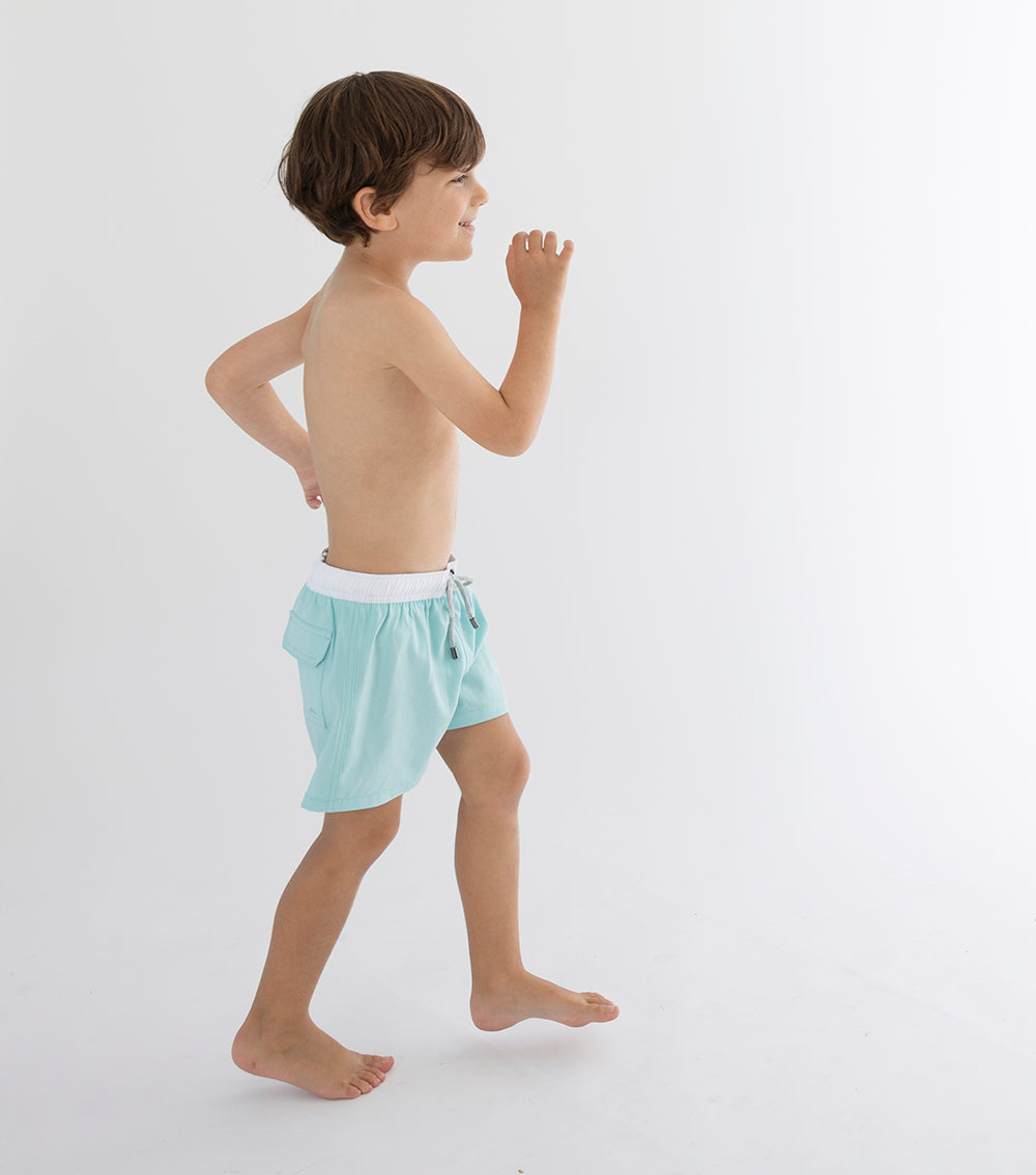 Aqua Young boy wearing light blue swim shorts on a white background