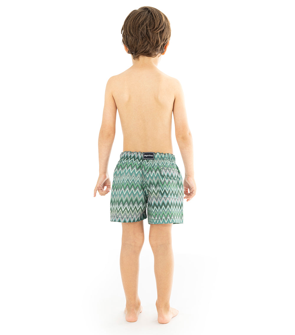 Chevron Young boy wearing green zigzag patterned swim shorts on a white background