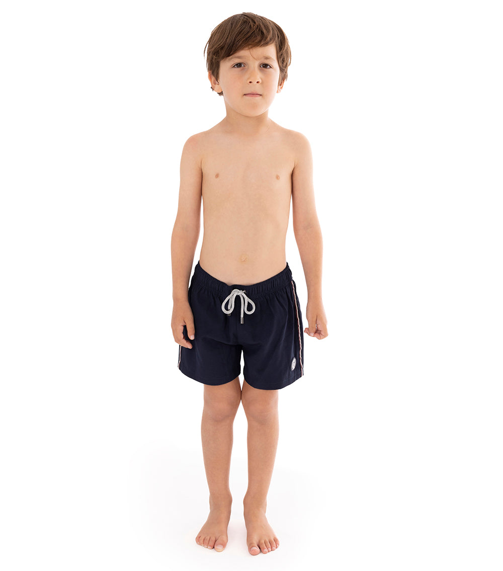 Navy Young boy wearing navy swim shorts on a white background