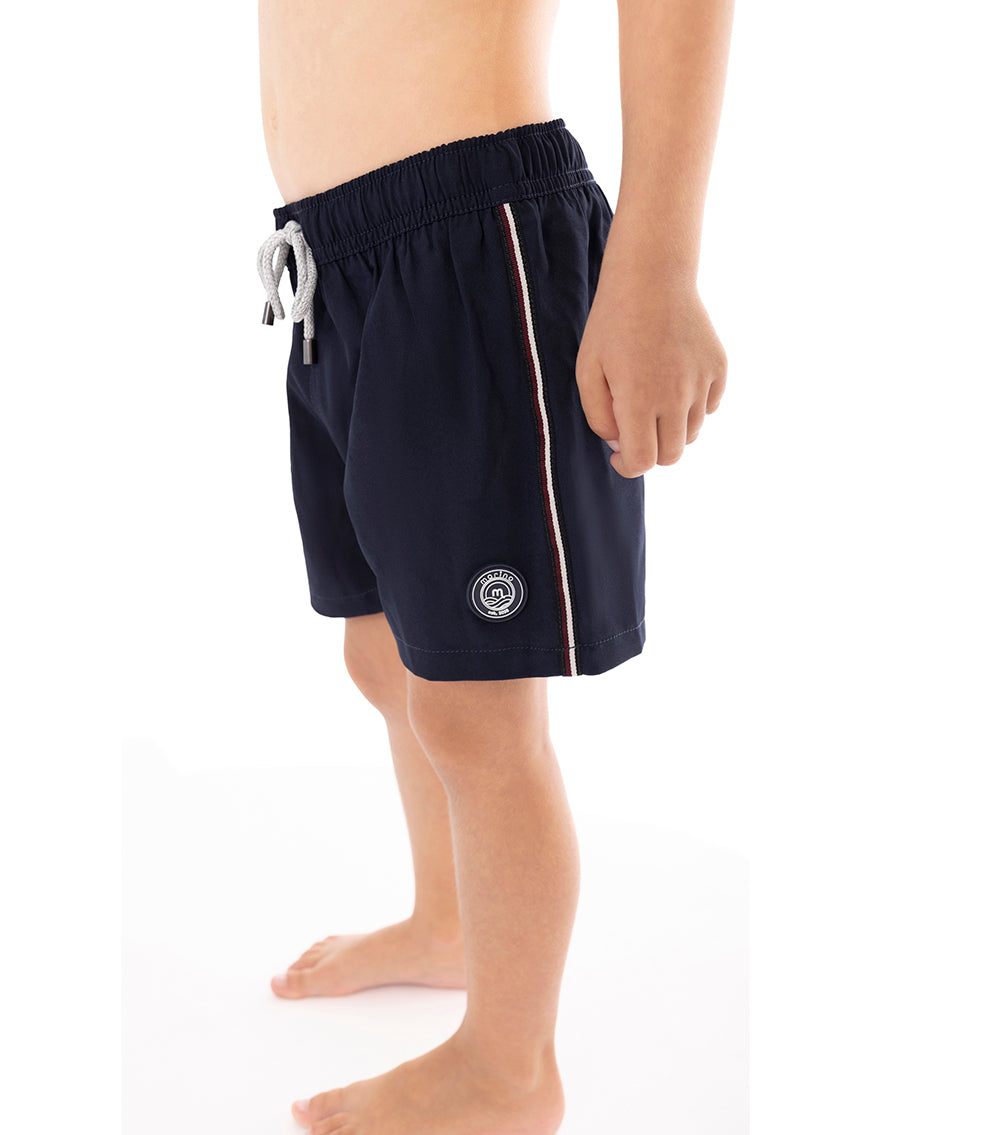 Navy Young boy wearing navy swim shorts on a white background