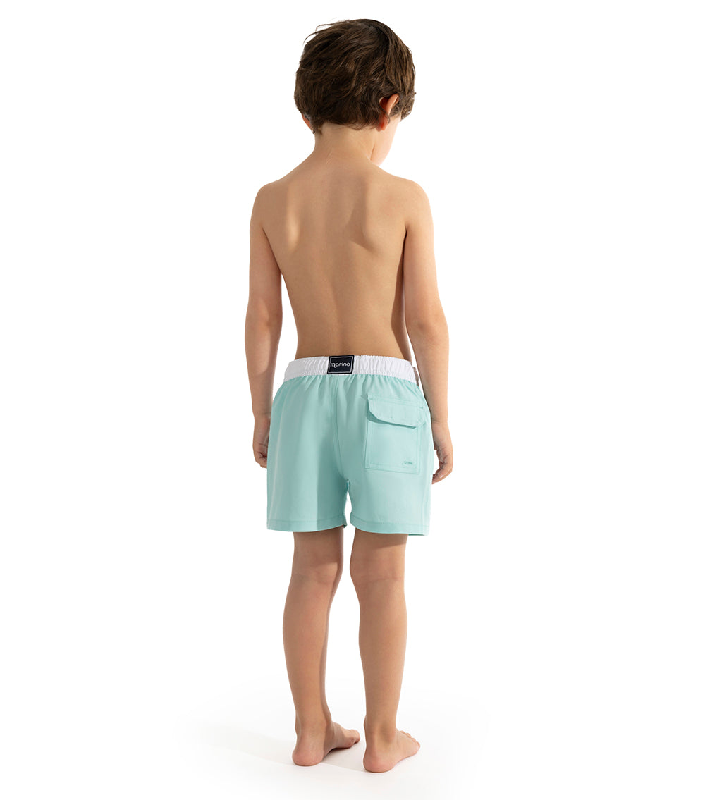 Aqua Young boy wearing light blue aquamarine swim shorts on a white background