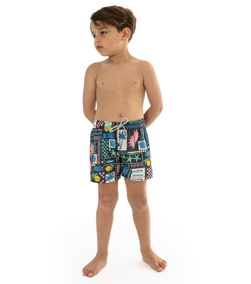 Capri Black Child wearing colorful patterned swim shorts on a white background