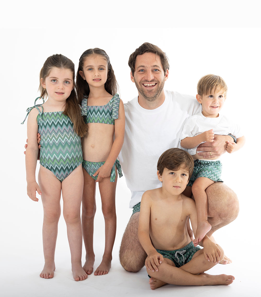 Chevron Family of five wearing matching green zigzag swimwear on a white background