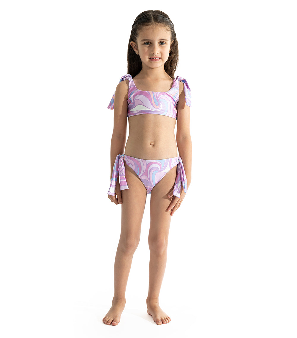 Groovy Young girl wearing a purple and white patterned two-piece swimsuit on a white background