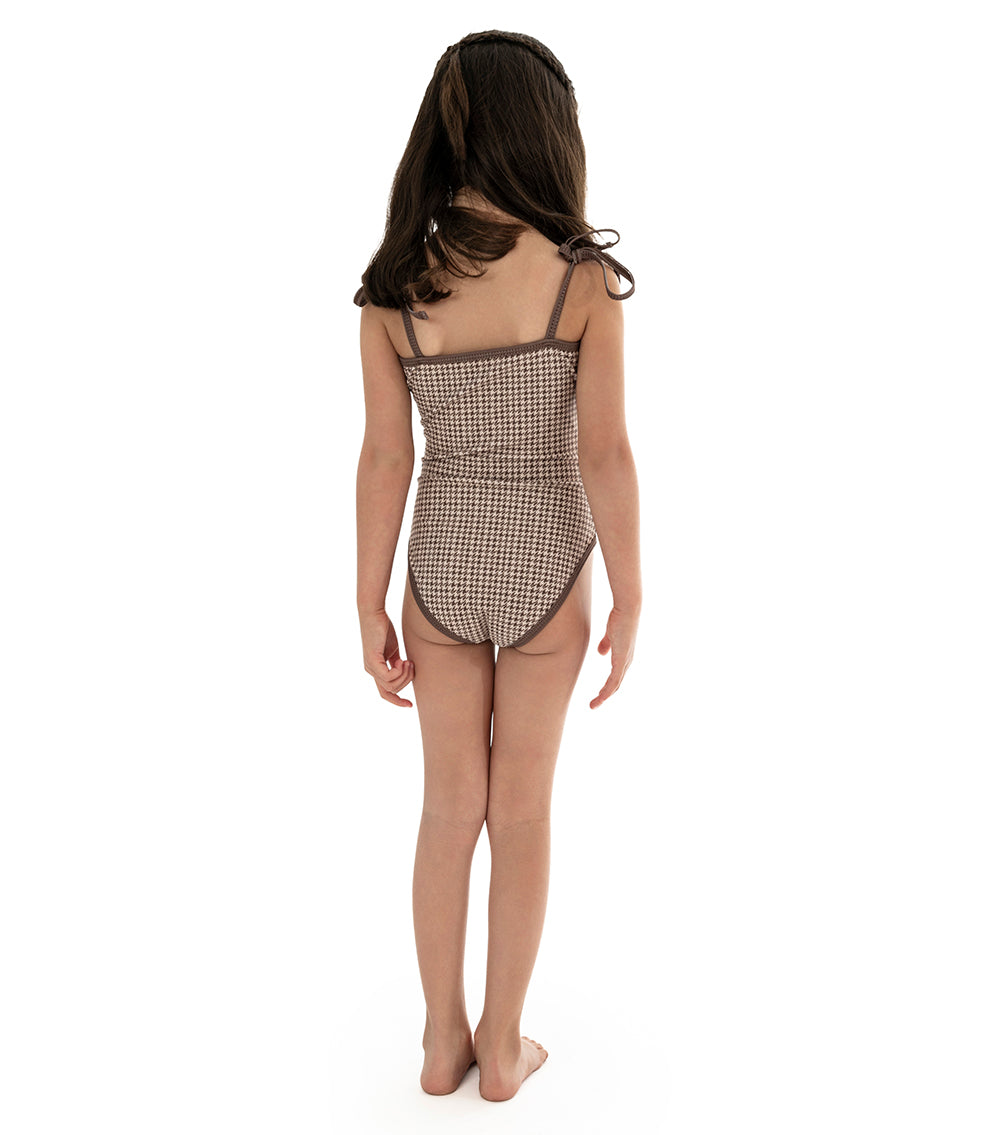 Houndstooth young girl wearing a brown printed swimsuit on a white background