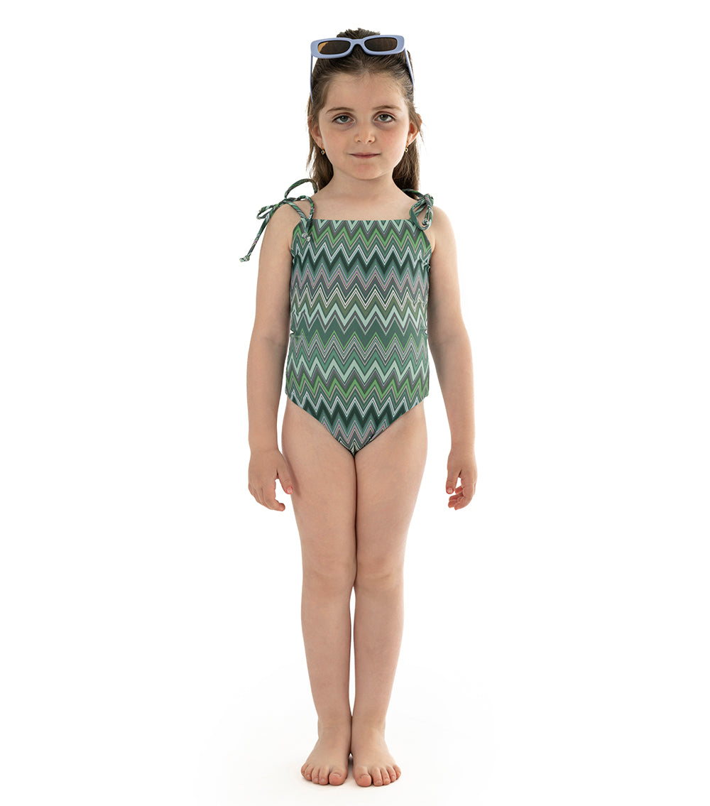 chevron Young girl wearing a green zigzag patterned swimsuit on a white background