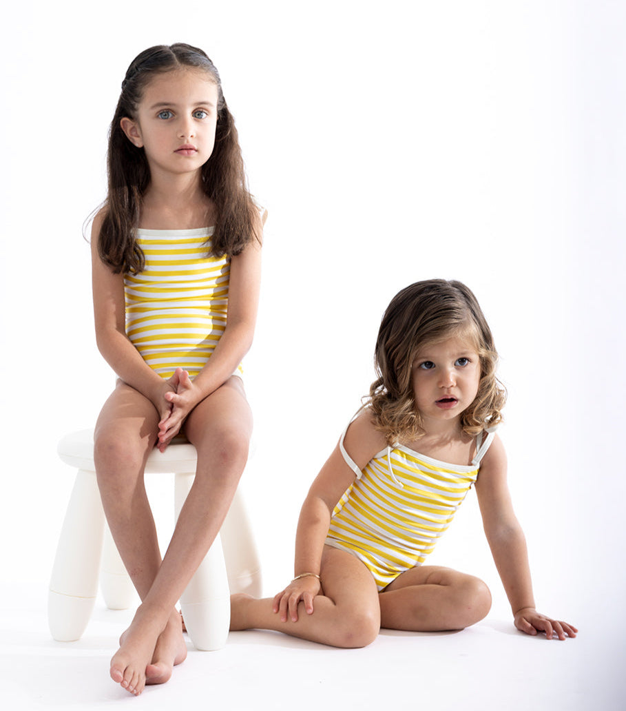 Yellow Stripes Two young girls wearing yellow and white striped swimsuits on a white background