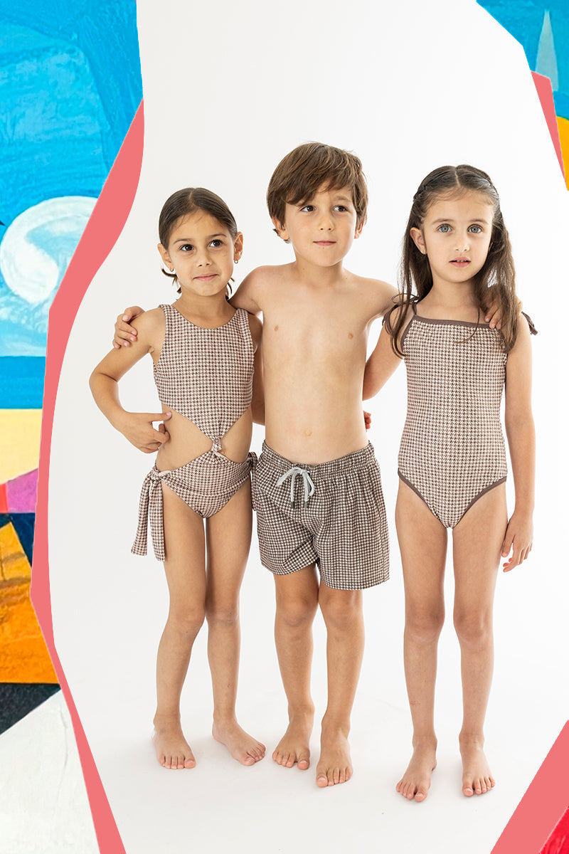 three children wearing matching brown houndstooth printed swimsuits
