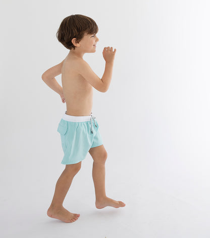 Aqua Young boy wearing light blue swim shorts on a white background