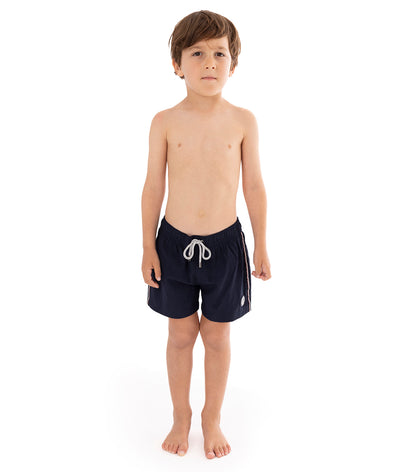 Navy Young boy wearing navy swim shorts on a white background