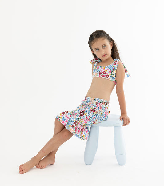 Flowers Girl wearing floral swimsuit with matching skirt on a chair
