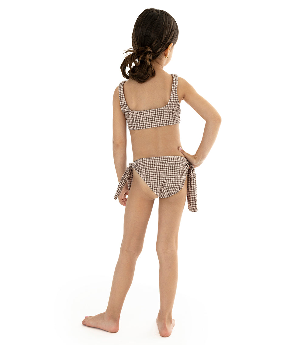 Houndstooth Young girl wearing a brown printed swimsuit on a white background
