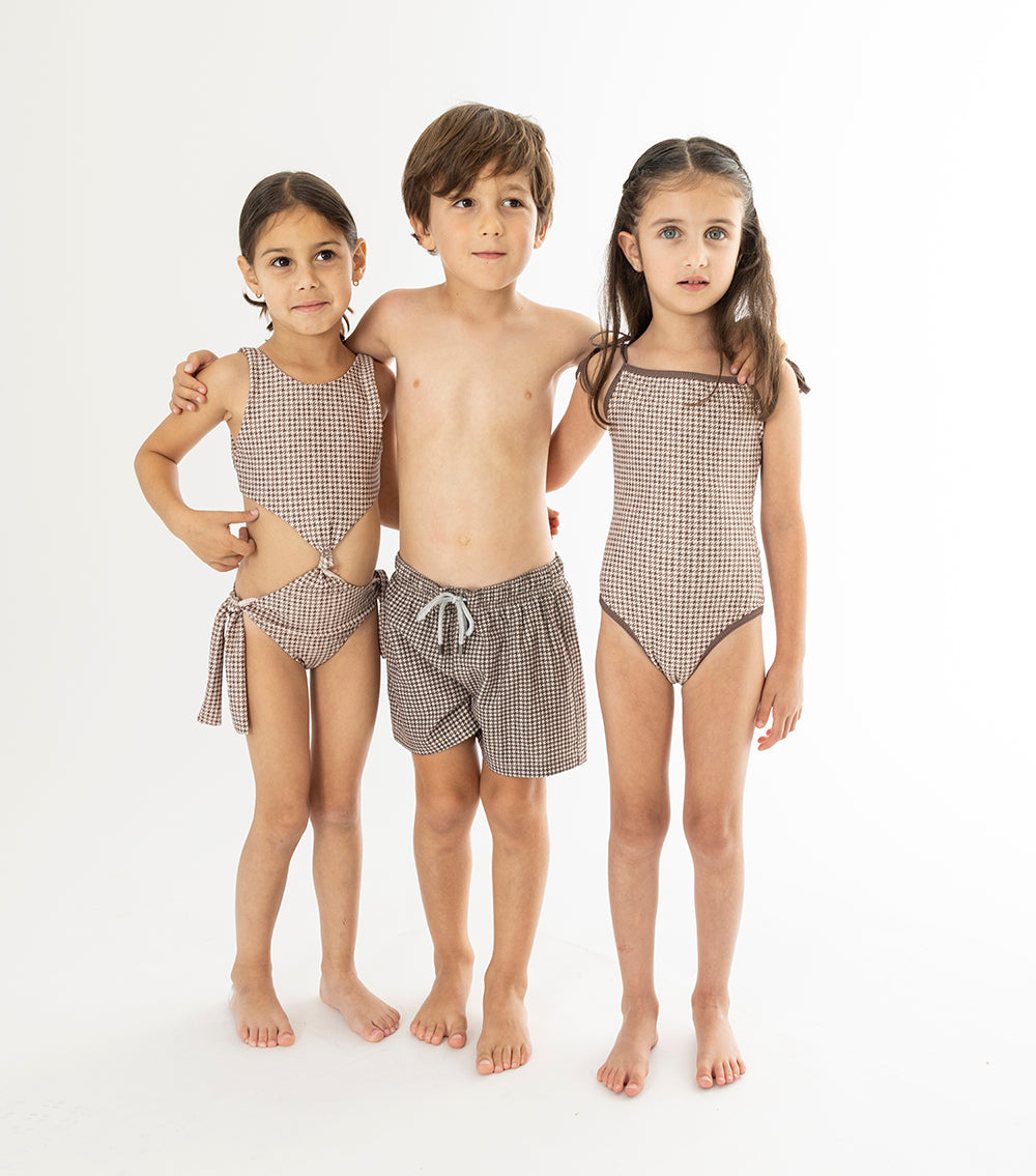 Houndstooth Three children wearing matching brown swimwear on a white background