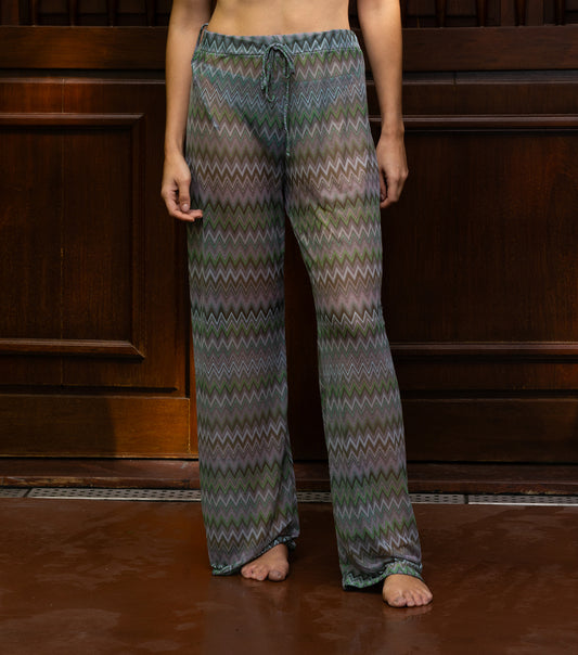 chevron woman wearing patterned mesh pants standing against a wooden panel background