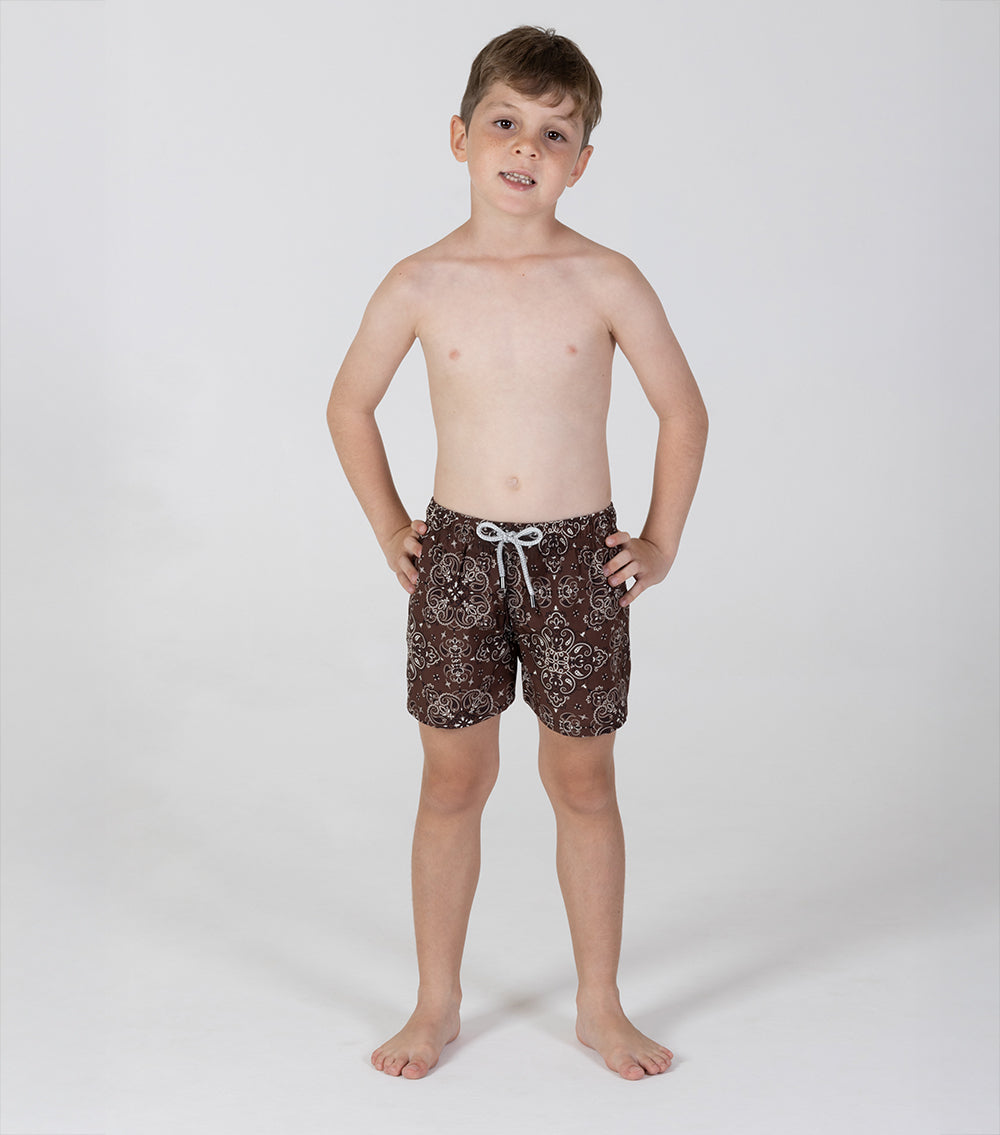 brown bandana Young boy wearing brown patterned shorts on a white background