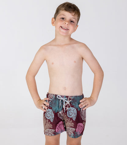 burgundy corals Young boy wearing colorful floral swim shorts on a white background