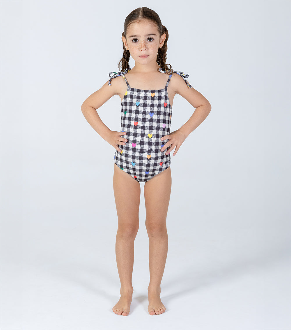 gingham emoji Young girl wearing a black and white checkered swimsuit with colorful heart patterns on a white background