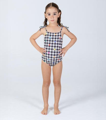 gingham emoji Young girl wearing a black and white checkered swimsuit with colorful heart patterns on a white background