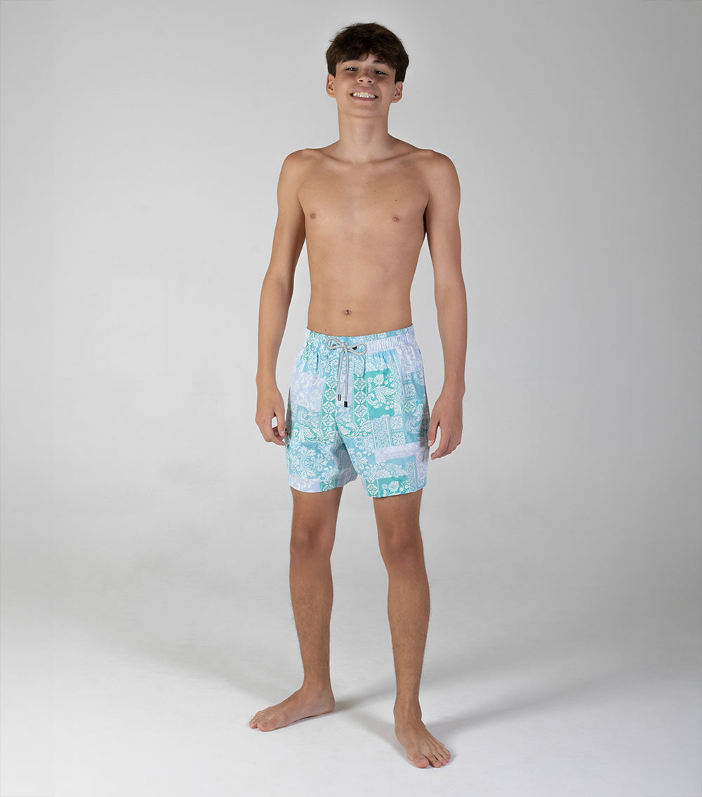 paisley Young man wearing light blue swim shorts with a pattern on a white background