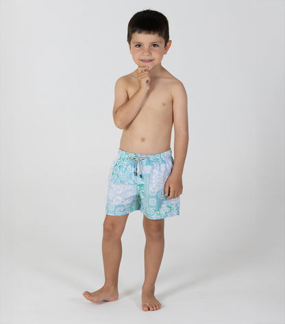 paisley Young boy wearing light blue swim shorts with a floral pattern on a white background