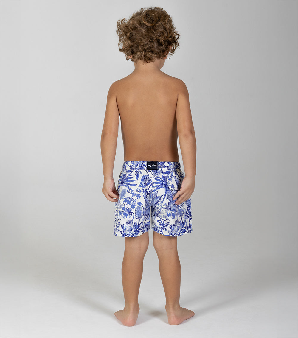 tropical Child wearing blue floral swim shorts on a plain background