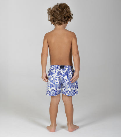 tropical Child wearing blue floral swim shorts on a plain background